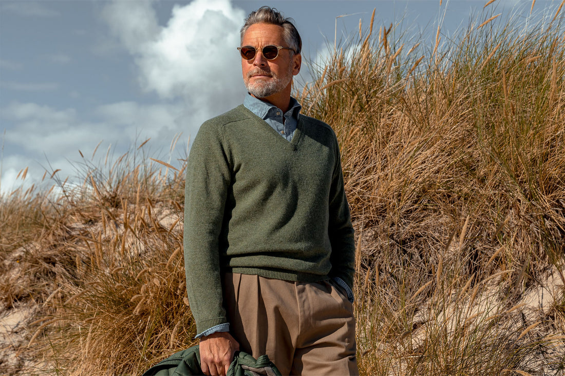Mature man in smart casual attire standing by the dunes on a sunny day.