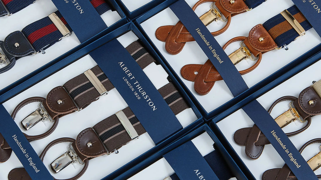 An array of neatly arranged elastic belts with leather details, presented in an open box packaging.