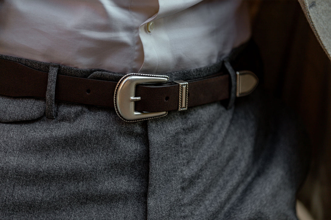Close-up of a brown belt on gray trousers.