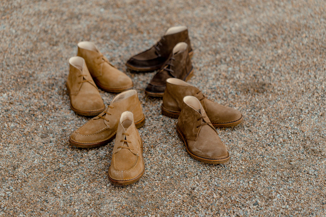 Three pairs of brown shoes arranged on a gravel surface.