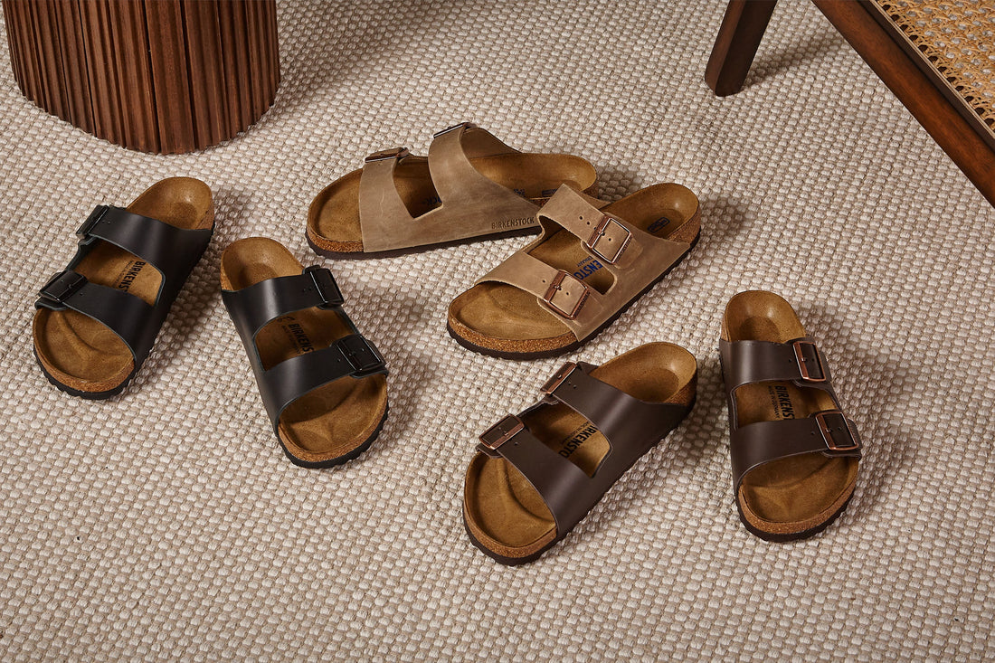 Four pairs of open-toed sandals displayed on a textured floor.