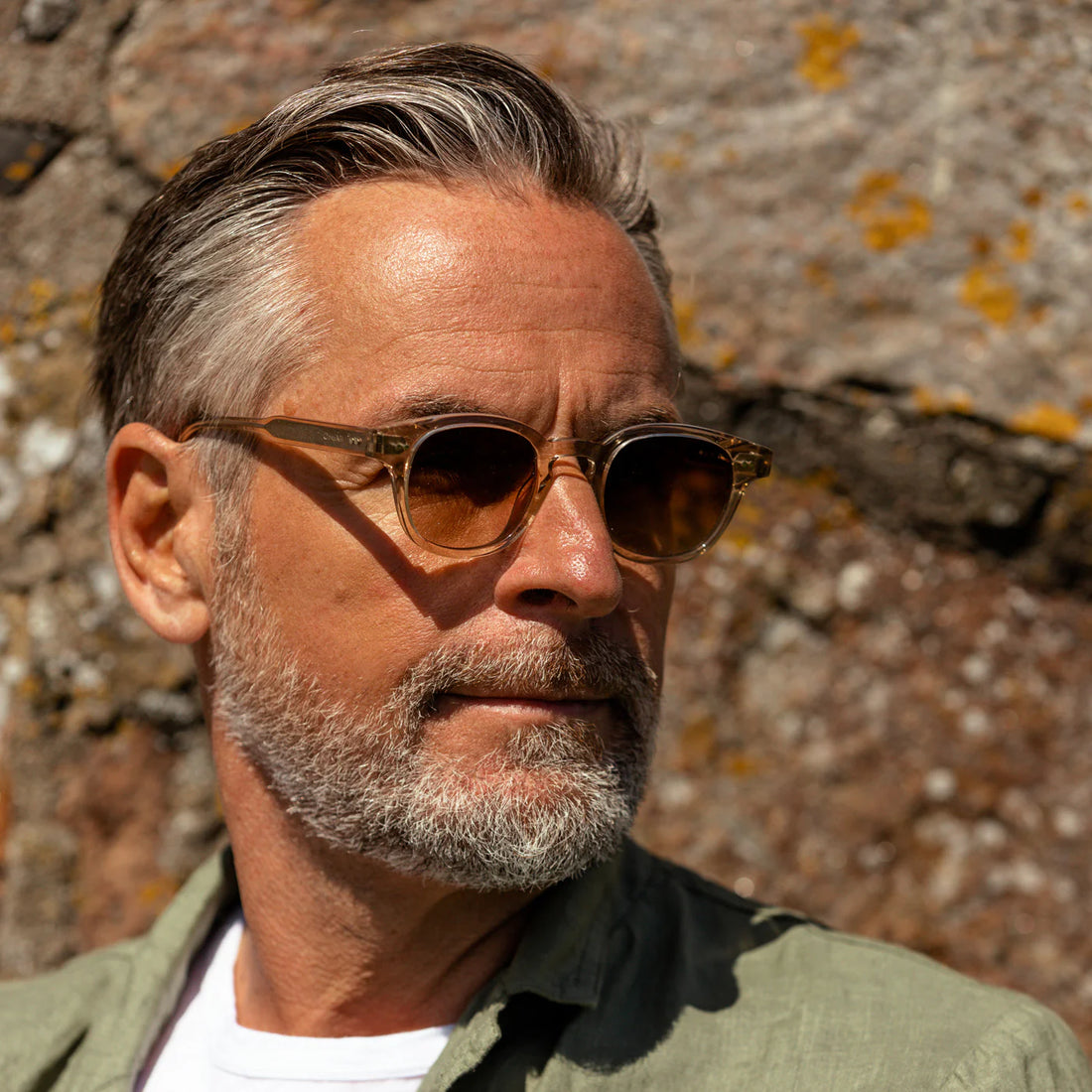 Bearded middle-aged man wearing sunglasses and a turtleneck, looking thoughtfully to the side.