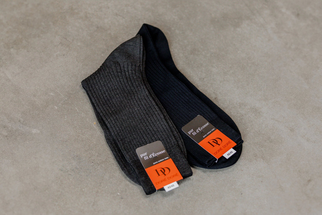 A pair of new black socks with orange price tags on a concrete surface.