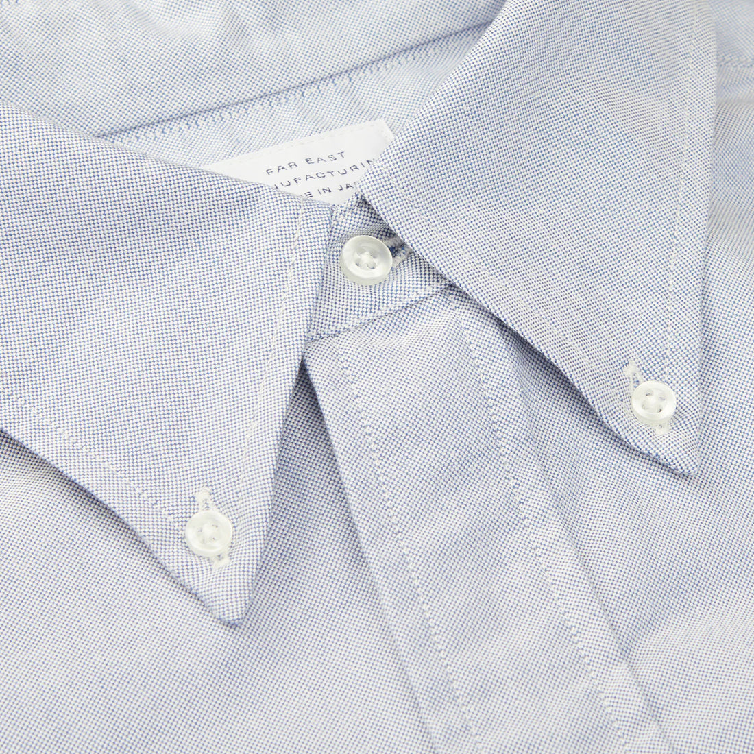 Close-up of a light blue button-up shirt with a focus on the collar and top button.
