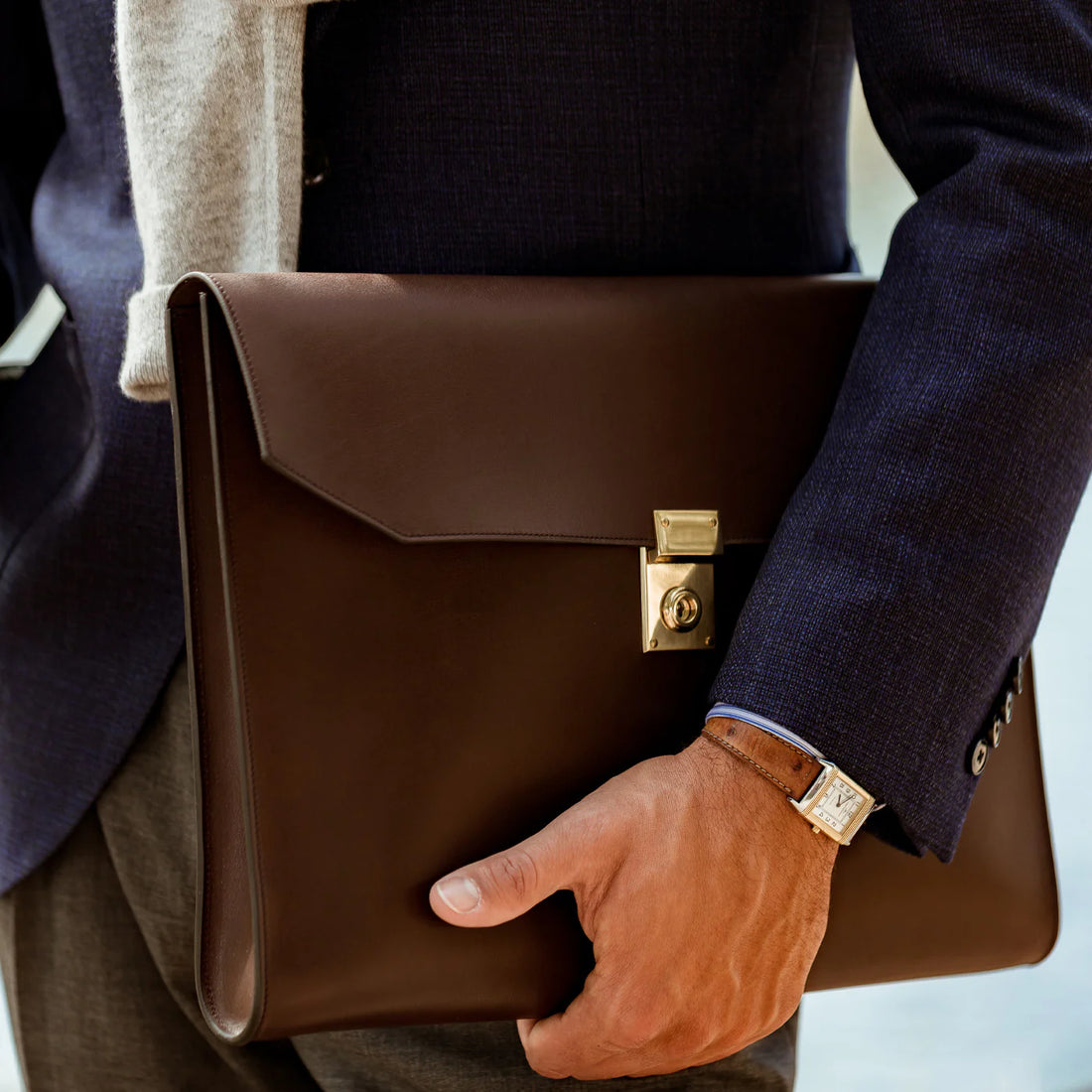 A person clad in a business suit carrying a brown leather briefcase.