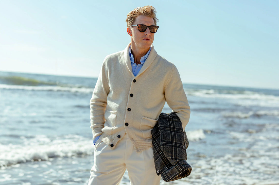 Man in smart casual attire standing on a beach.