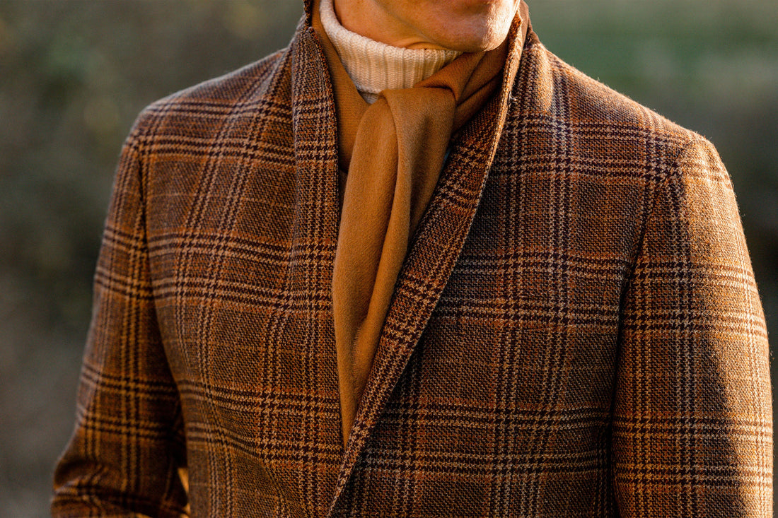Close-up of a person wearing a plaid blazer and a beige turtleneck sweater.