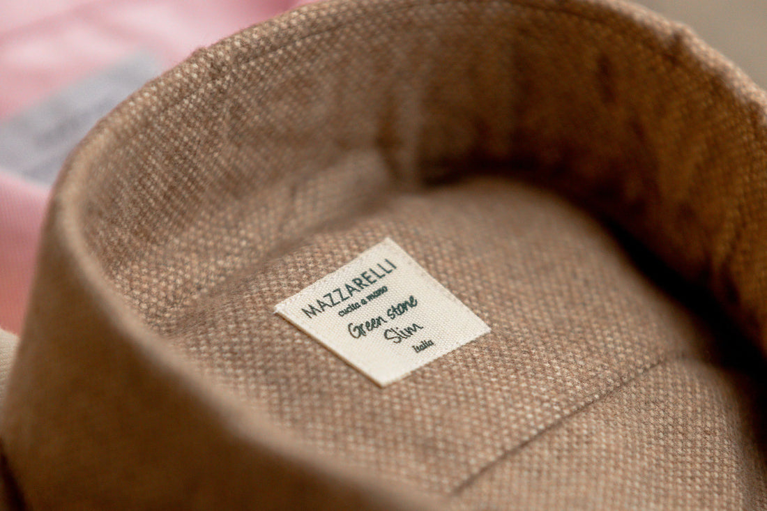Close-up of a clothing label reading "matazarelli green 100% cashmere" inside a beige fabric.