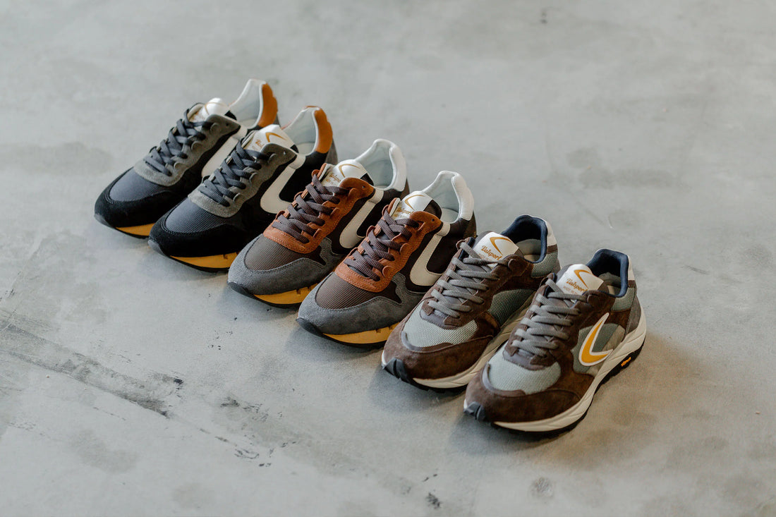 Four pairs of sneakers with different color accents arranged on a concrete floor.