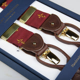 A pair of Bordeaux with Gold French Lily 35 mm Braces with leather detailing and gold clips, displayed on a navy blue presentation box labeled "Handmade by Albert Thurston, London.