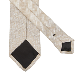 A pair of Amanda Christensen Light Beige Herringbone Linen Lined Ties on a black background.