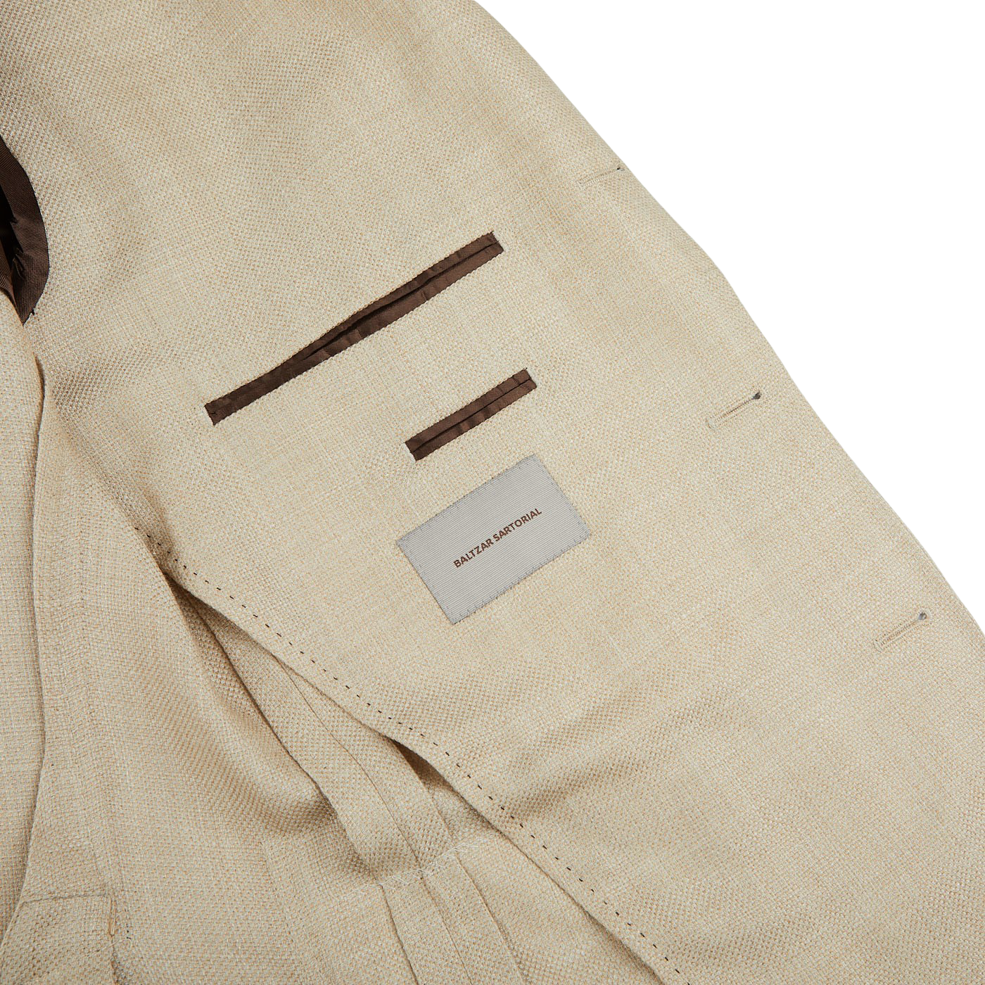 A close up of a Beige Melange Wool Silk Linen Blazer with a brown label by Baltzar Sartorial.