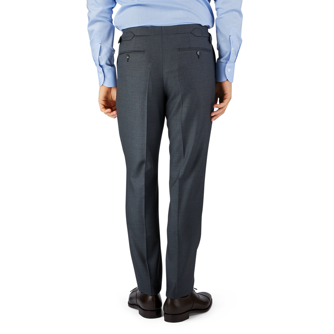A man wearing a blue shirt and Grey Super 100's Wool Flat Front Suit Trousers by Baltzar Sartorial, standing on a black surface against a blue and gray background.
