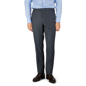 Man in a blue shirt and Baltzar Sartorial Grey Super 100's Wool Flat Front Suit Trousers standing against a white background, focus on trousers.