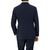 A man viewed from behind, wearing a well-fitted Navy Blue Super 100s Wool DB Suit Jacket by Baltzar Sartorial, standing against a striped, translucent background.