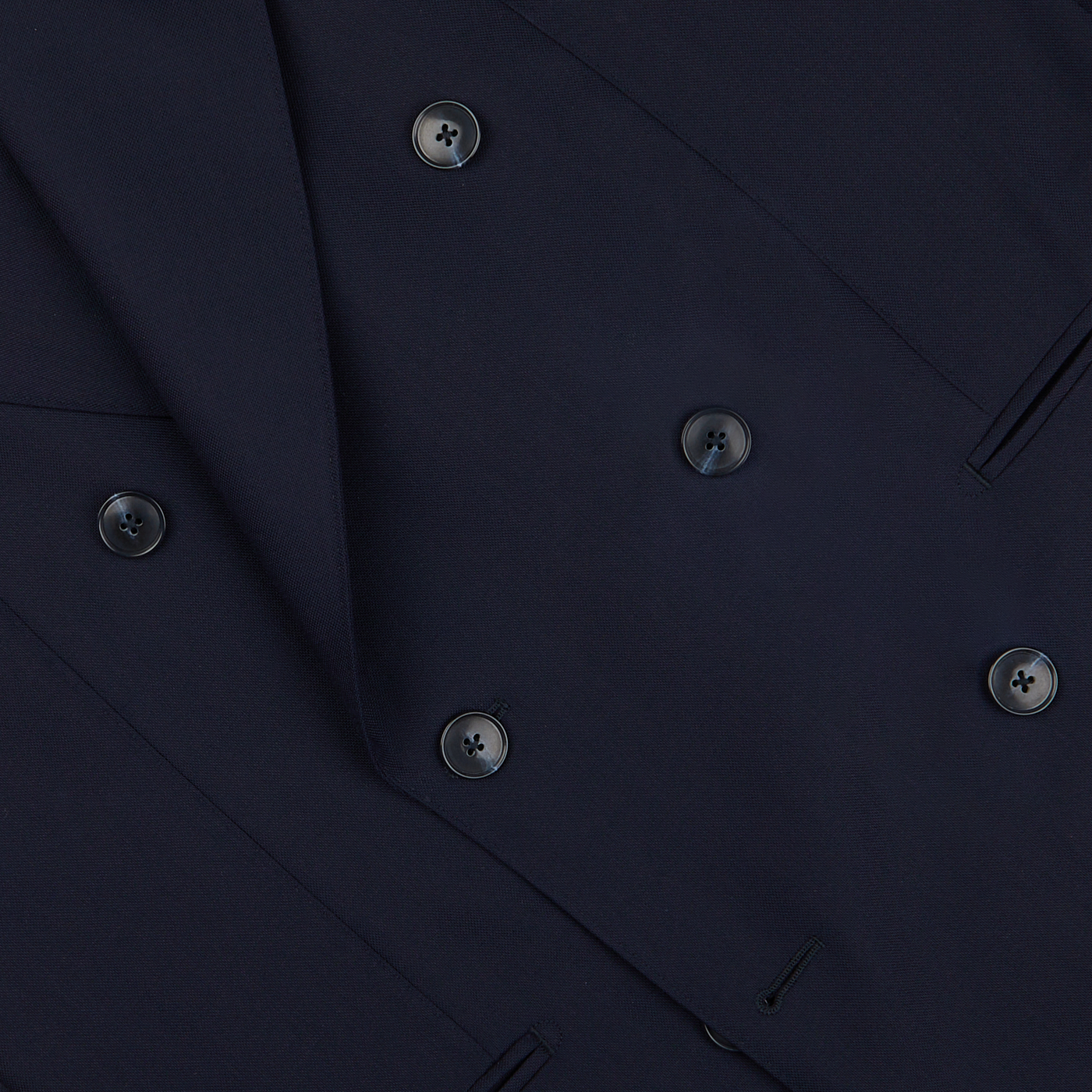 Close-up of a Baltzar Sartorial navy blue double-breasted suit jacket made from super 100’s wool fabric, showing detailed stitching and buttons.