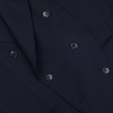 Close-up of a Baltzar Sartorial navy blue double-breasted suit jacket made from super 100’s wool fabric, showing detailed stitching and buttons.