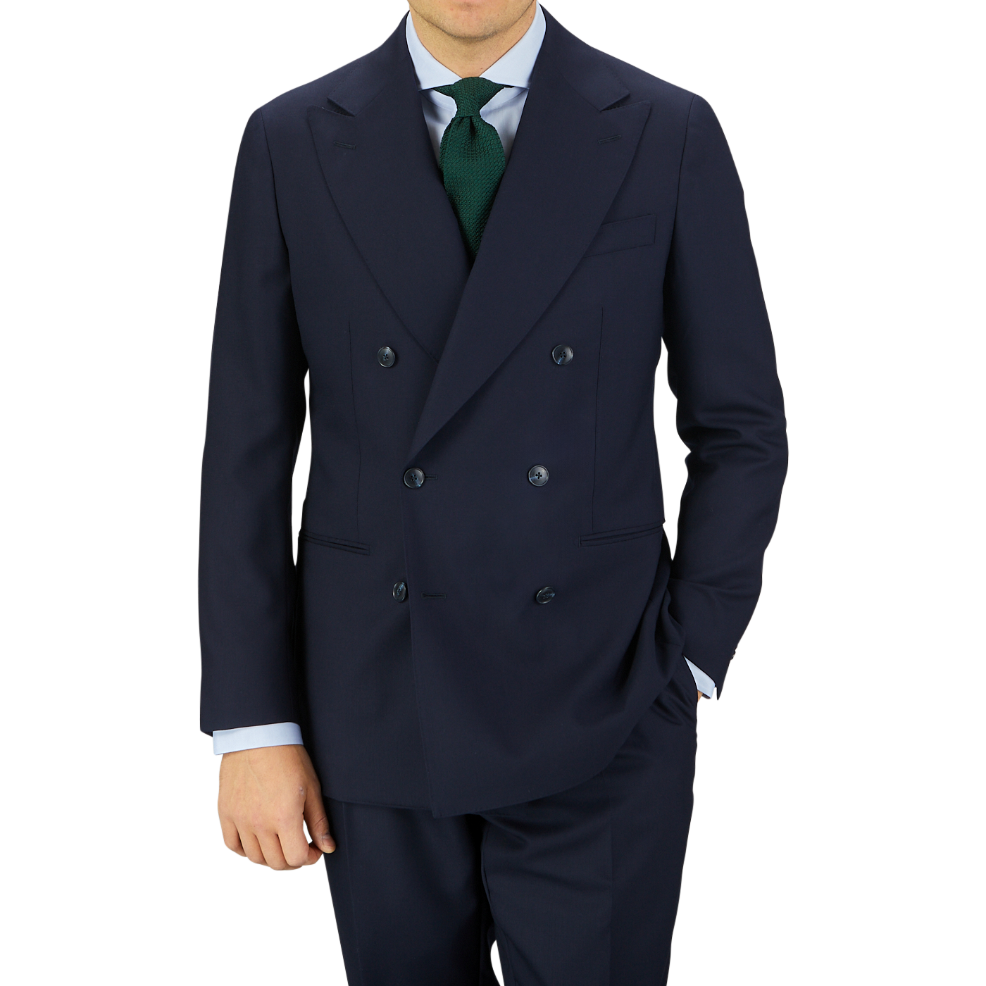 Man wearing a Baltzar Sartorial Navy Blue Super 100s Wool DB Suit Jacket with a green sweater and dark blue tie, standing against a light gray background.