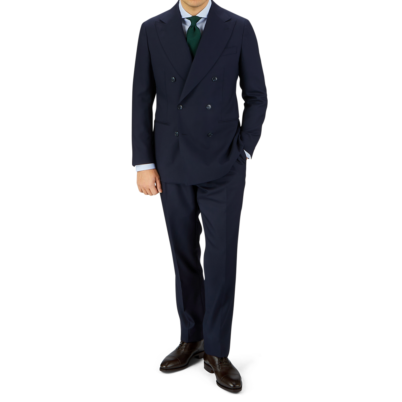 A man in a tailored Navy Blue Super 100s Wool DB Suit Jacket by Baltzar Sartorial, white shirt, and green tie, standing against a gray and white background.