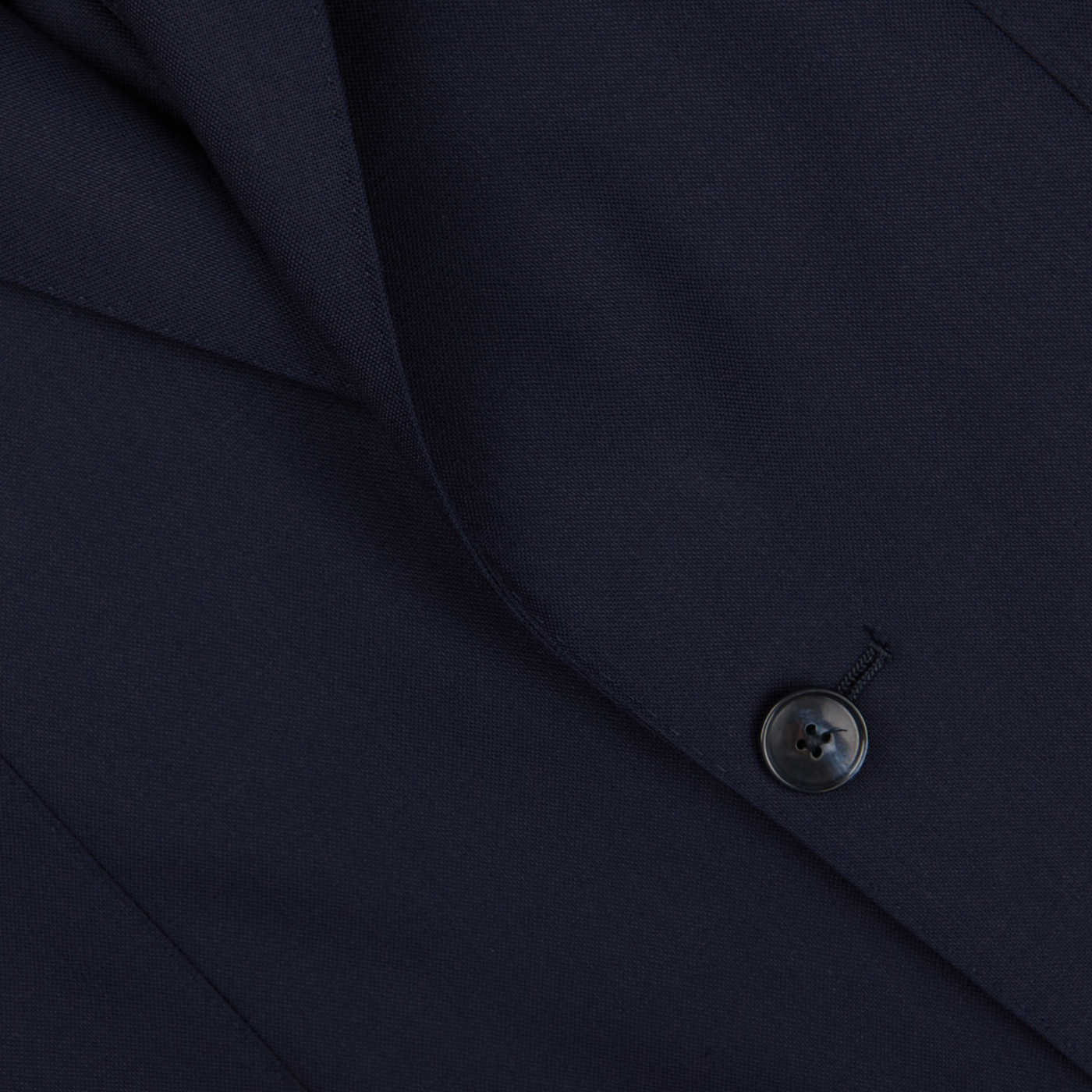Close-up of a Baltzar Sartorial navy Super 100's wool suit jacket detail showing fabric texture and a button.