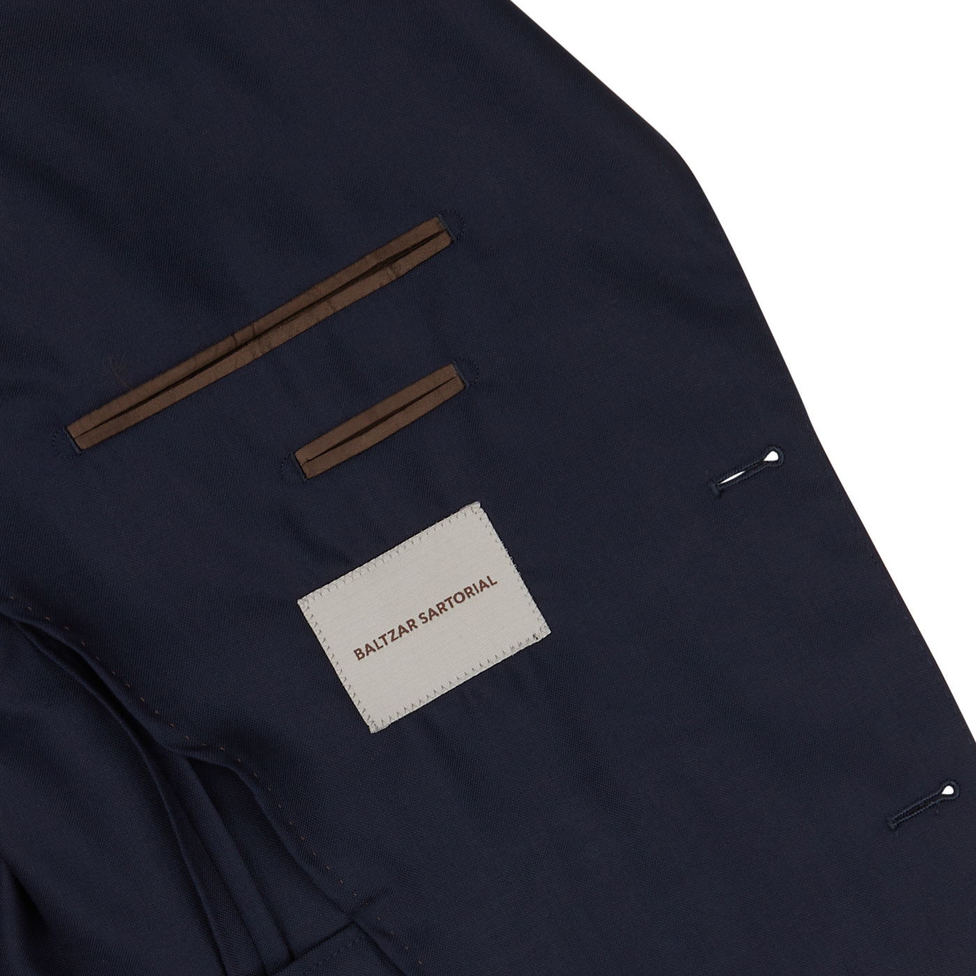 Close-up of a Navy Super 100's Wool Suit Jacket by Baltzar Sartorial with visible stitching details on white background.