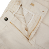 A pair of Cream Linen Twill Drawstring Trousers by Berwich with gold zippers.