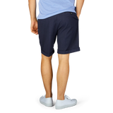 Man standing side-on showcasing Berwich navy blue cotton blend pleated shorts and white sneakers.