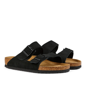A pair of black suede leather Birkenstock Arizona sandals with two straps, buckles, and cork footbeds.