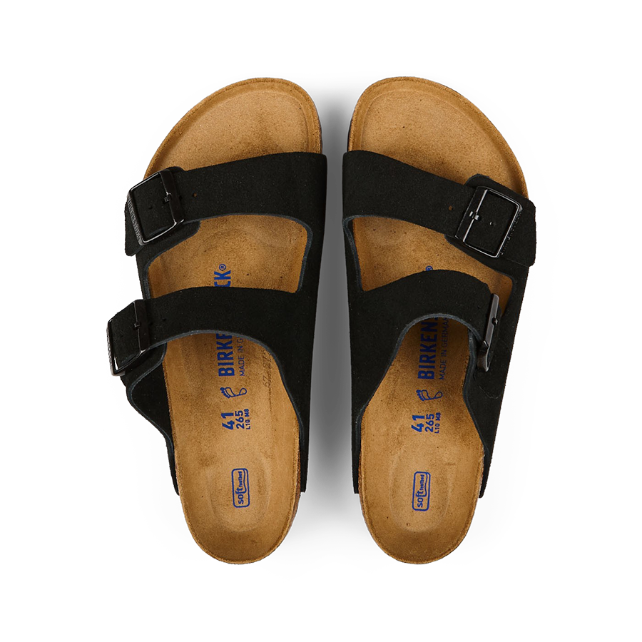 A pair of Black Suede Leather Arizona sandals by Birkenstock with buckles on a black background.
