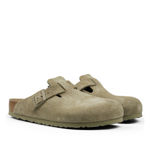A pair of Faded Khaki Suede Leather Birkenstock Boston slippers with buckles, displayed on a transparent background.
