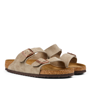 A pair of taupe beige suede leather Birkenstock Arizona sandals with cork footbeds and rubber soles.