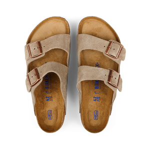 A pair of Taupe Beige Suede Leather Birkenstock Arizona Sandals displayed on a black background.