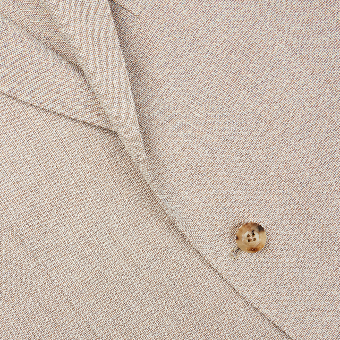 A close up of a cream beige Boglioli suit with a gold button showcasing exquisite craftsmanship.