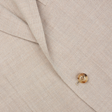 A close up of a cream beige Boglioli suit with a gold button showcasing exquisite craftsmanship.