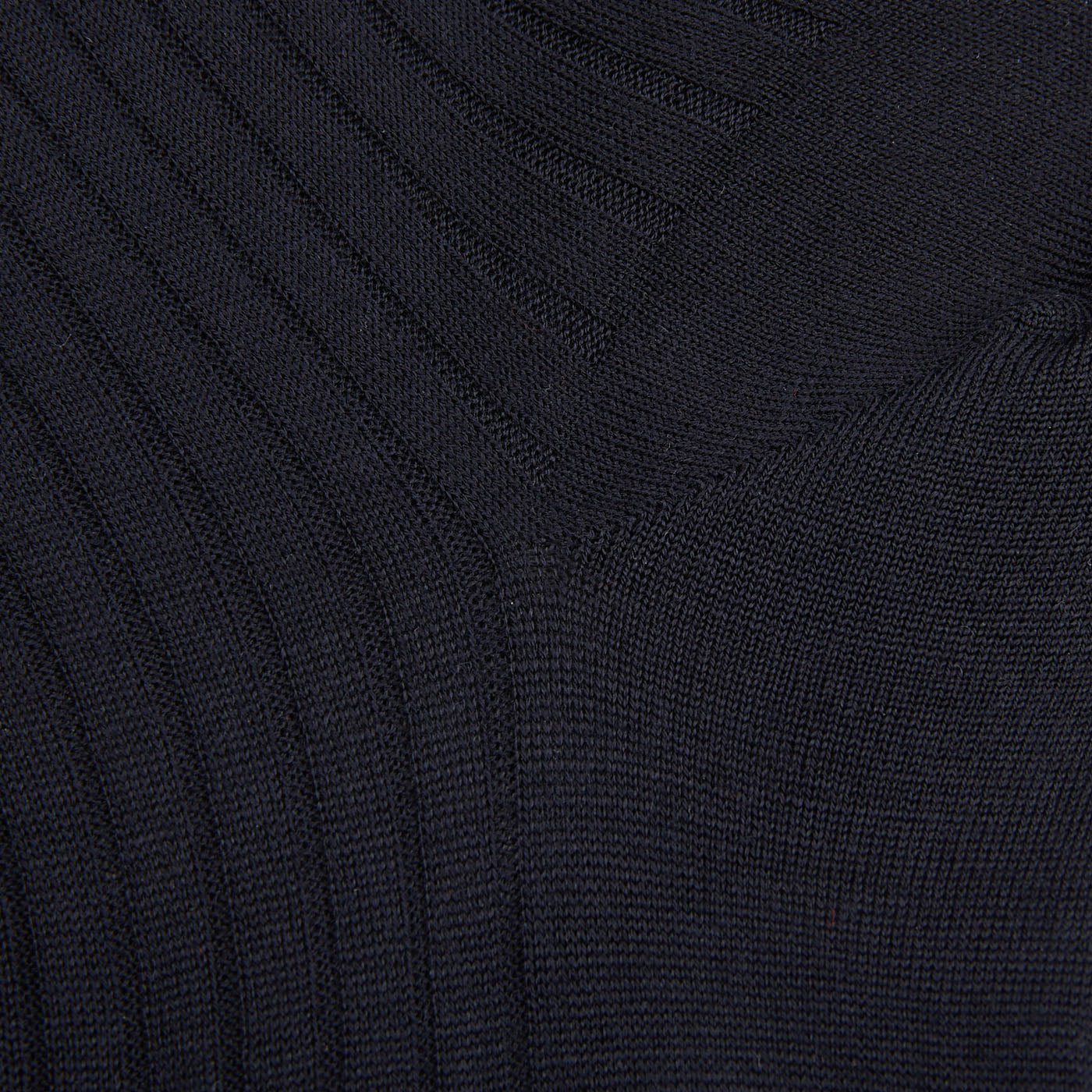 A close up of a black sweater with ribbed cuffs and Bresciani navy blue ribbed wool nylon socks.