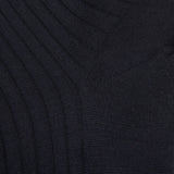 A close up of a black sweater with ribbed cuffs and Bresciani navy blue ribbed wool nylon socks.