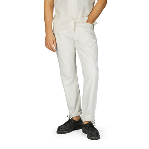Man wearing a white shirt and Ecru Stone Washed Kuroki Cotton M5 Jeans by C.O.F Studio with dark shoes, standing against a plain background, cropped at the waist.