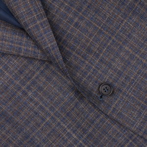 Close-up of a textured blue gingham checked wool silk linen Canali blazer with a visible button, highlighting the detailed weave and pattern.