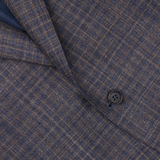 Close-up of a textured blue gingham checked wool silk linen Canali blazer with a visible button, highlighting the detailed weave and pattern.
