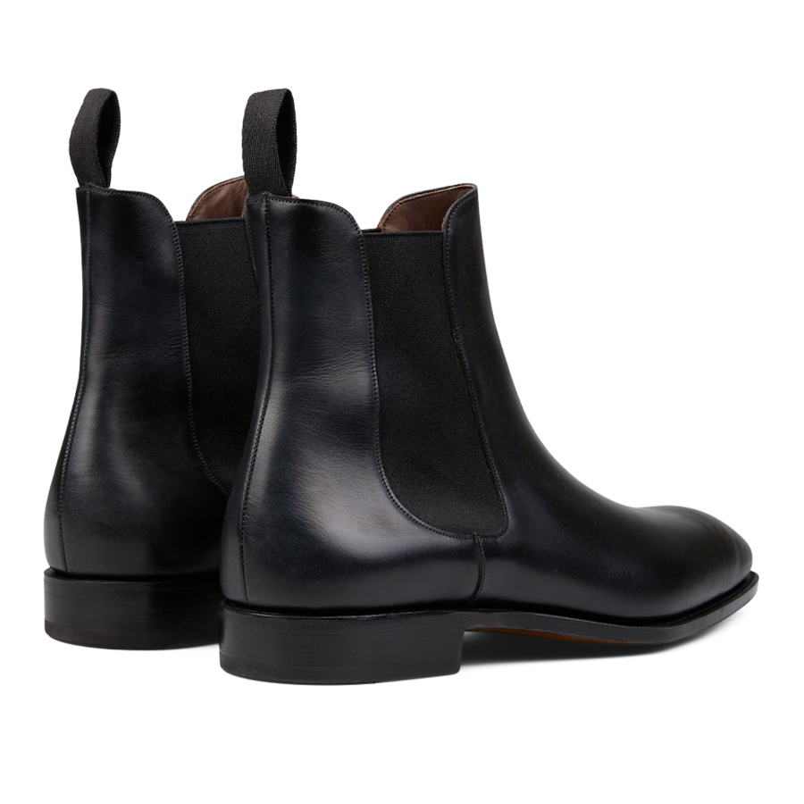 A pair of sleek black leather Simpson Chelsea boots with brown lining and pull tabs on a white background, crafted by expert craftsmen.