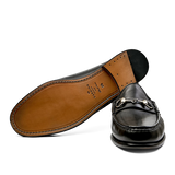 A single black Funchal Leather Xim Horsebit loafer by Carmina displayed above its sole.