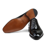 Black Rain Patent Leather Carmina Oxford Shoes with a tan sole on a transparent background.