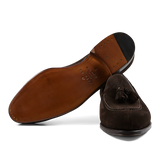 A pair of Brown Suede Forest Tassel Loafers with leather soles crafted by expert craftsmen, displayed on a transparent background, made by Carmina.