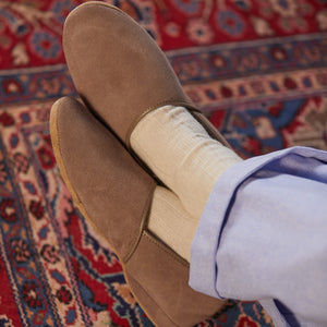 A person wearing a pair of Derek Rose handmade Taupe Suede Sheepskin Closed-Back Slippers on a rug.