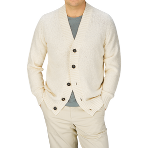 Man wearing a Ecru White Knitted Cotton Cardigan by Drumohr over a gray shirt with light-colored pants.