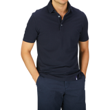 Man standing with hands on hips wearing a dark blue Drumohr Navy Blue Cotton Piquet Polo Shirt and navy trousers.