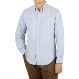 A man wearing a Far East Manufacturing light blue cotton oxford BD regular shirt and brown pants made of cotton fabric.