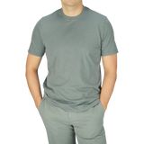 A man wearing a luxury Fedeli Olive Green Organic Cotton T-shirt and gray pants.