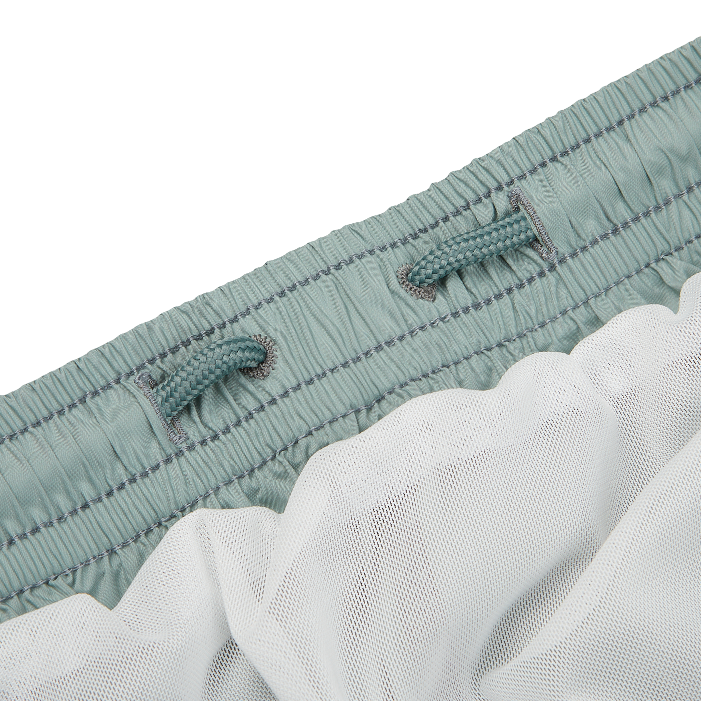Close-up of a light blue Fedeli Sage Green Madeira swim shorts waistband with elastic gathers and two drawstrings, partially covered by a layer of white mesh fabric.