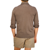 The back view of a man wearing a Fedeli Washed Brown Organic Cotton LS Polo Shirt and shorts, casually blending luxury into his outfit.